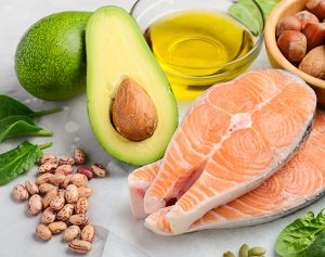 Aufgeschnittener Lachs, eine Avocado und Nüsse sind hübsch auf einem Tisch drapiert.