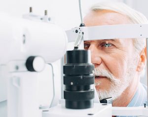 Ein Mann sitzt beim Augenarzt vor einem Gerät und schaut hinein.