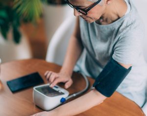Eine Frau misst ihren Blutdruck mit einem Blutdruckmessgerät.