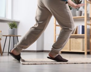 Header-Artikel: Jemand trägt Schlapfen und stolpert damit über die Kante eines Teppichs.