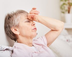 Header-Artikel: Frau lehnt müde an der Wand und legt ihre Hand auf die Schläfe.