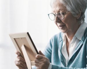 Artikel-Header_ Frau schaut traurig auf das Bild eines Verstorbenen.