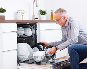Header-Artikel: Mann räumt Geschirrspüler ein.