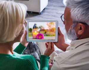 Header-Artikel: Ehepaar schaut in ein Tablet indem eine Kerze und eine Blume zu sehen ist.