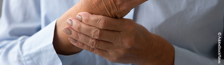 Großaufnahme einer Hand, die das schmerzhafte Handgelenk der anderen Hand umfasst. 